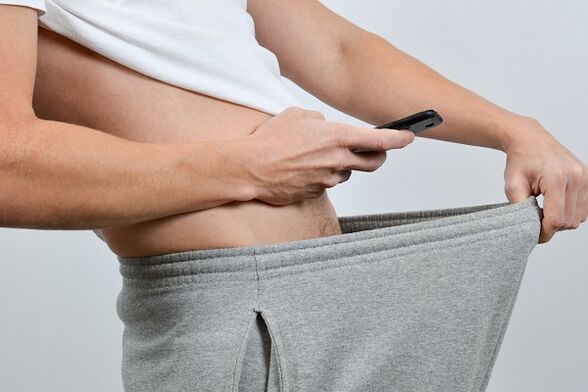 A man looks at an enlarged penis through his pants